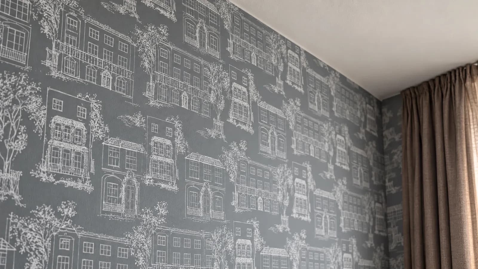 Detail der Häuser-Mustertapete am Anschluss zu Decke und Vorhang