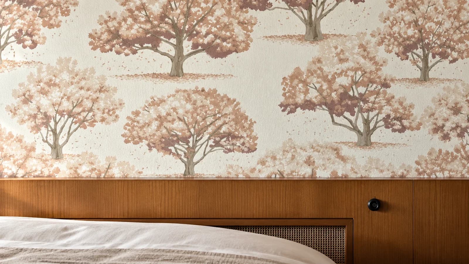 Schlafzimmer mit Designtapete Baum-Muster über dem Holz-Kopfteil des Betts